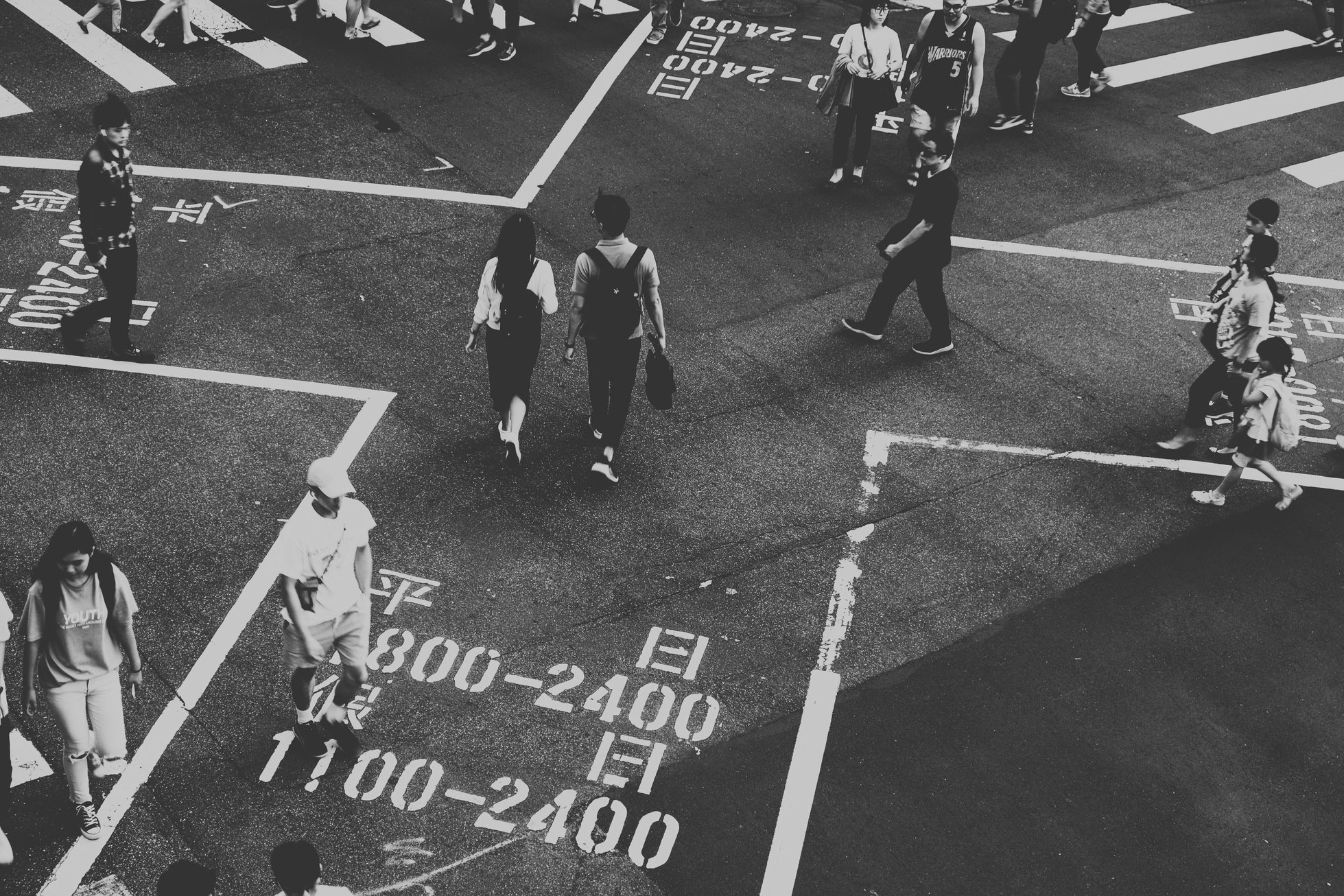 crowd crossing a street in black and white